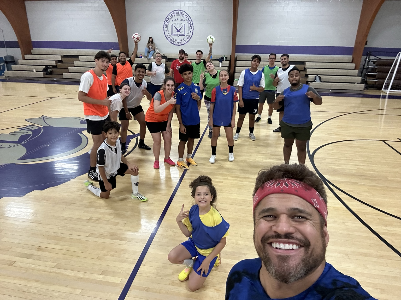 Romulo taking a selfie with a large indoor soccer group behind him